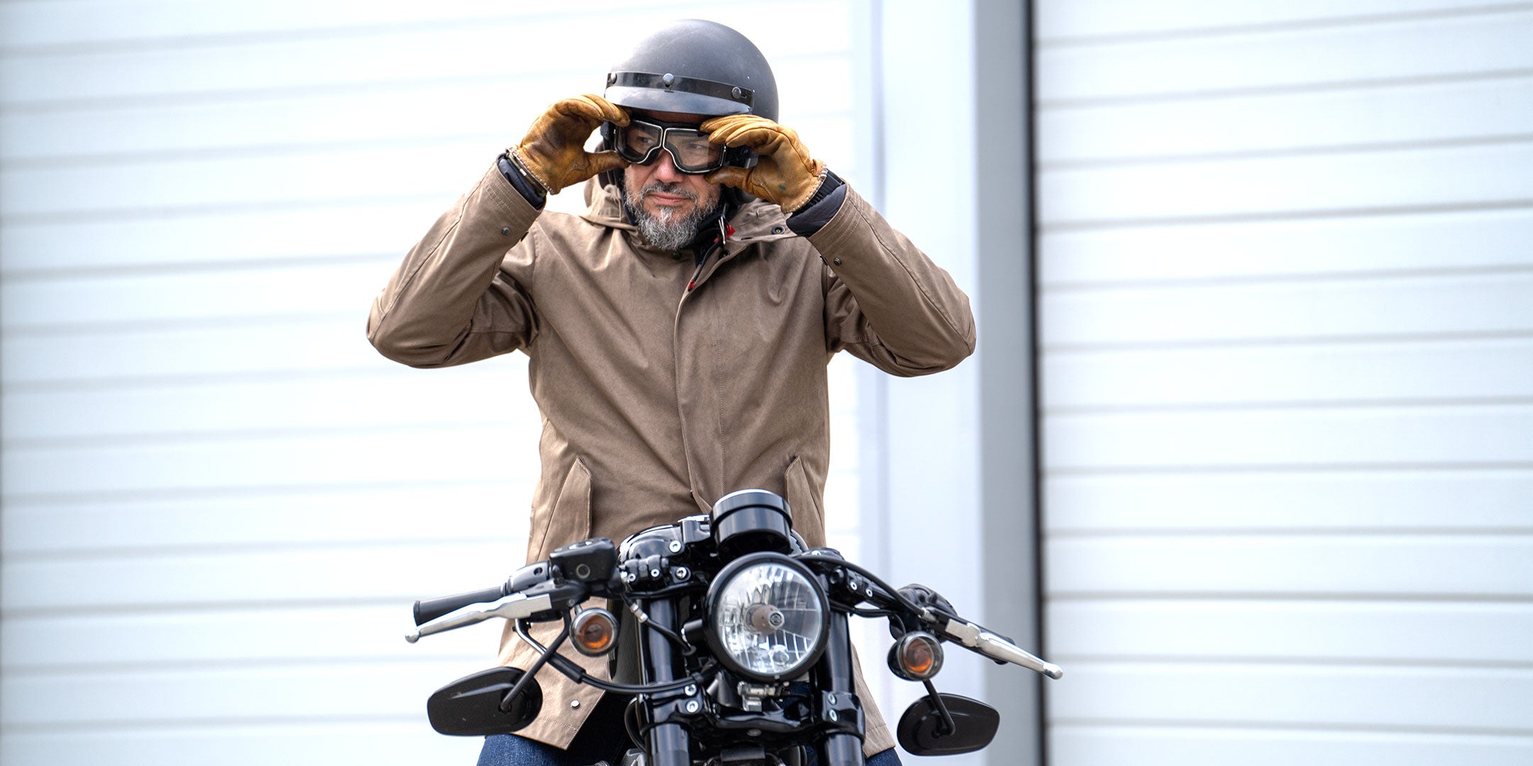 Model wearing a premium insualated and water resistant winter parka from for-legends.com by Caduff, crafted from exclusive high-density knit Japanese fabric, sitting on a harley davidson motorbike in a urban landscape. Perfect for commuting and urban mobility. / Modell trägt einen hochwertigen wasserabweisenden Winterparka von for-legends.com by Caduff aus einem exklusivem High-Density-Jersey aus Japan, sitzend auf einer Harley Davidson in einem urbanen Umfeld. Perfekt für Commuting und Urbane Mobilität.