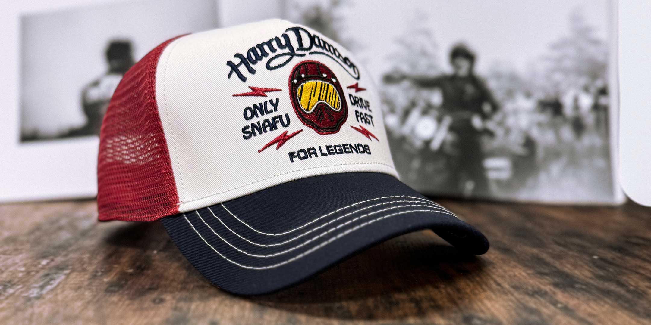 Burgunderfarbene Trucker Cap in Seitenansicht mit Festival-Szene im Hintergrund, For Legends x Harry Damson