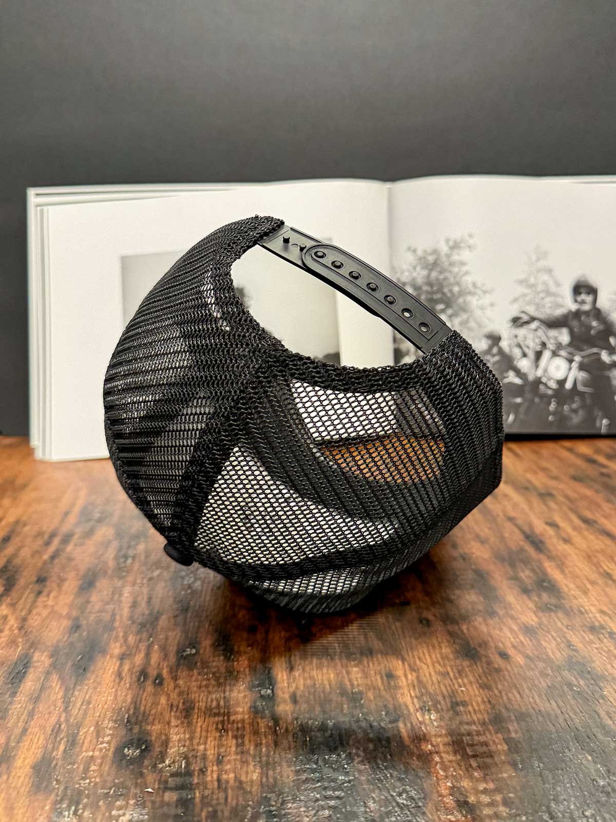 Schwarze Trucker Cap mit Mesh-Back und Snapback von hinten, Harley-Fahrer im schwarz-weißen Hintergrund, For Legends x Harry Damson