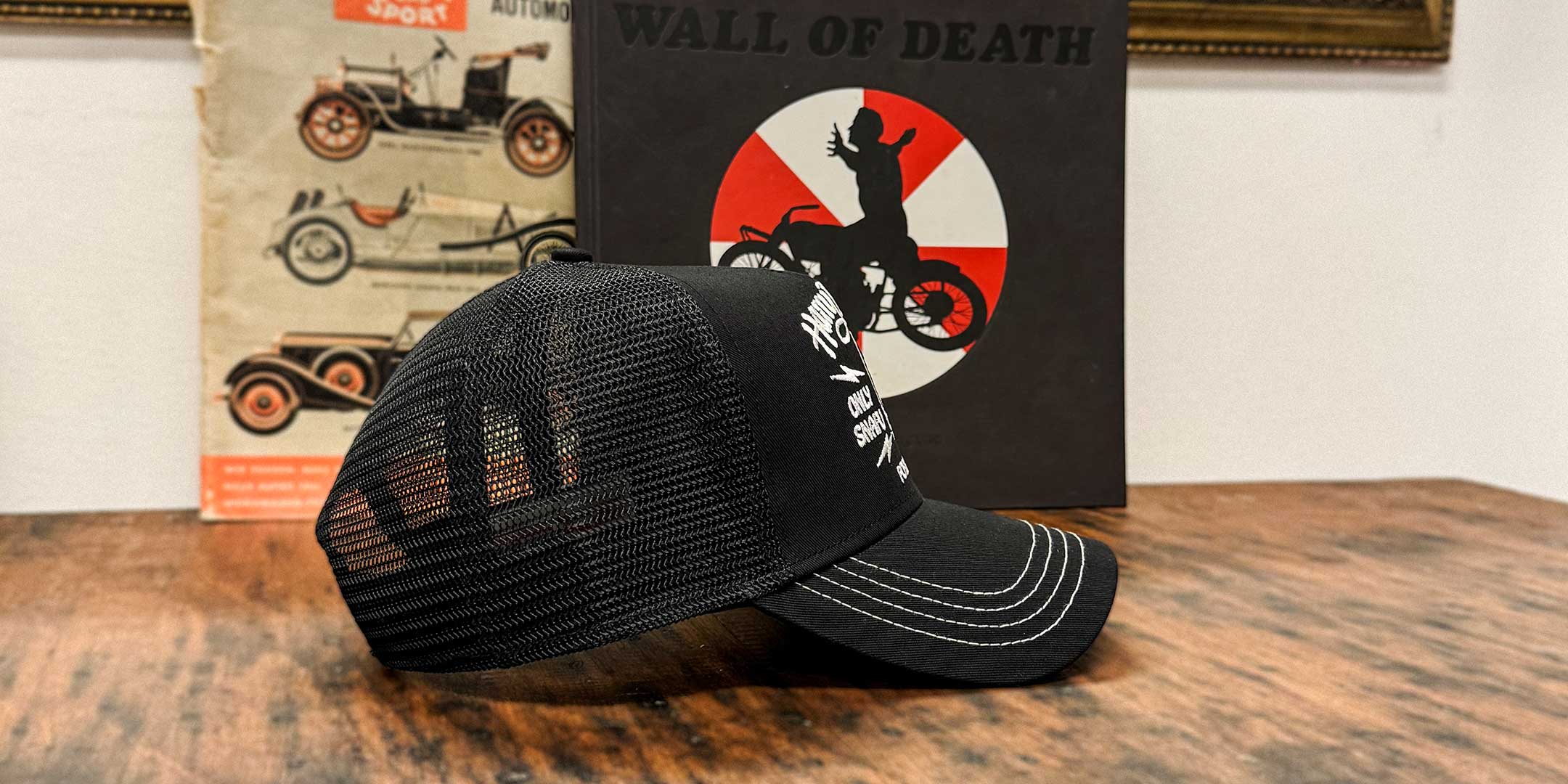 Schwarze Trucker Cap in Seitenansicht mit Biker, der die Arme ausstreckt, For Legends x Harry Damson