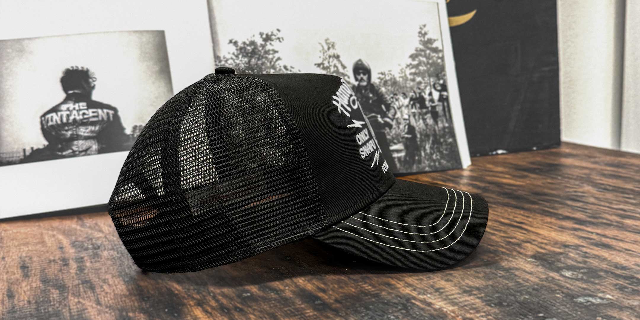 Schwarze Trucker Cap in Seitenansicht mit Festival-Szene im Hintergrund, For Legends x Harry Damson