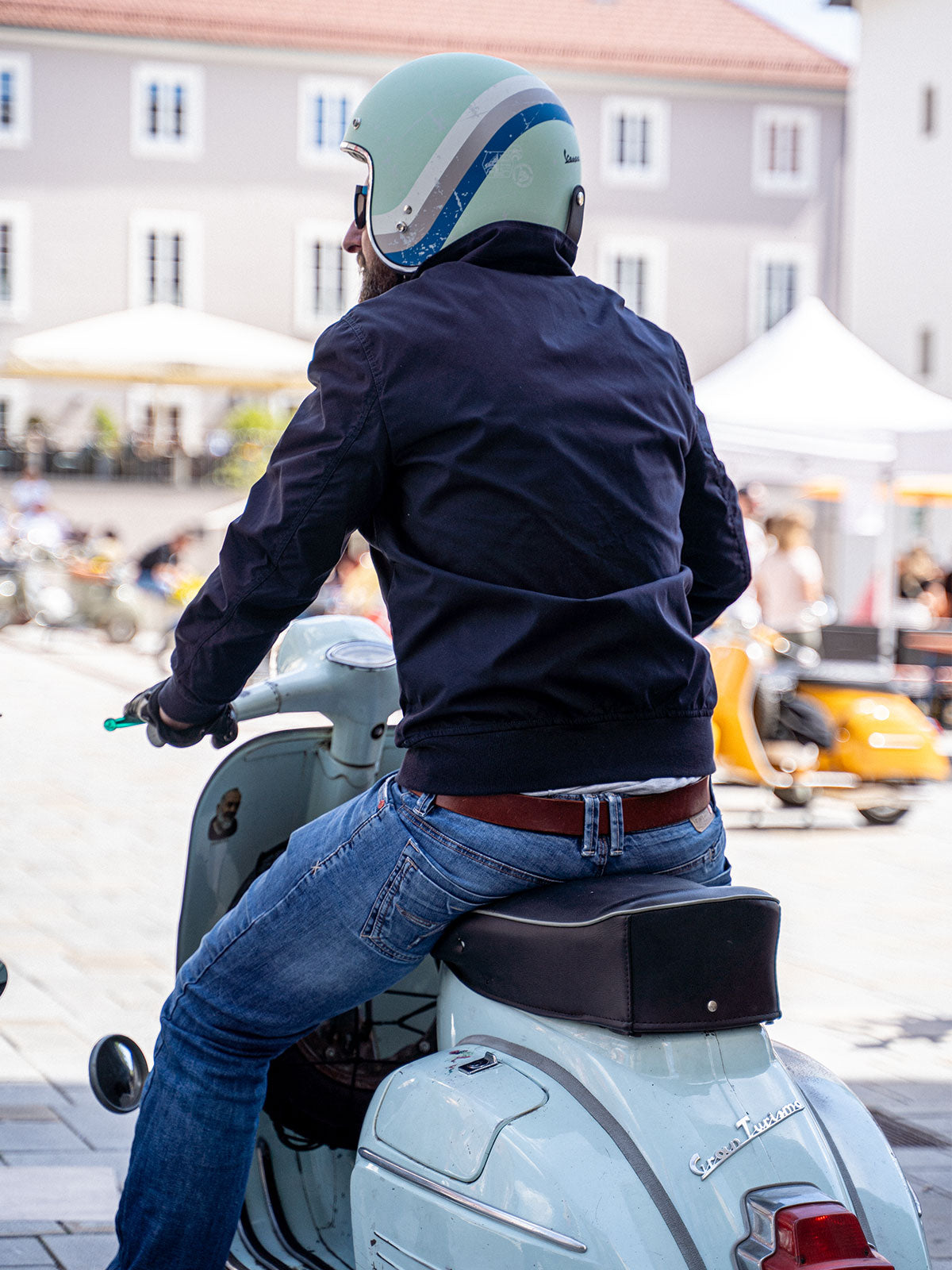 Ein Mann fährt auf einer Vespa und trägt einen abriebfesten Blouson der Marke For-Legends by Caduff, ideal für urban mobility - for-legends.com. A man rides a Vespa wearing an abrasion-resistant Blouson by For-Legends by Caduff, ideal for urban mobility - for-legends.com
