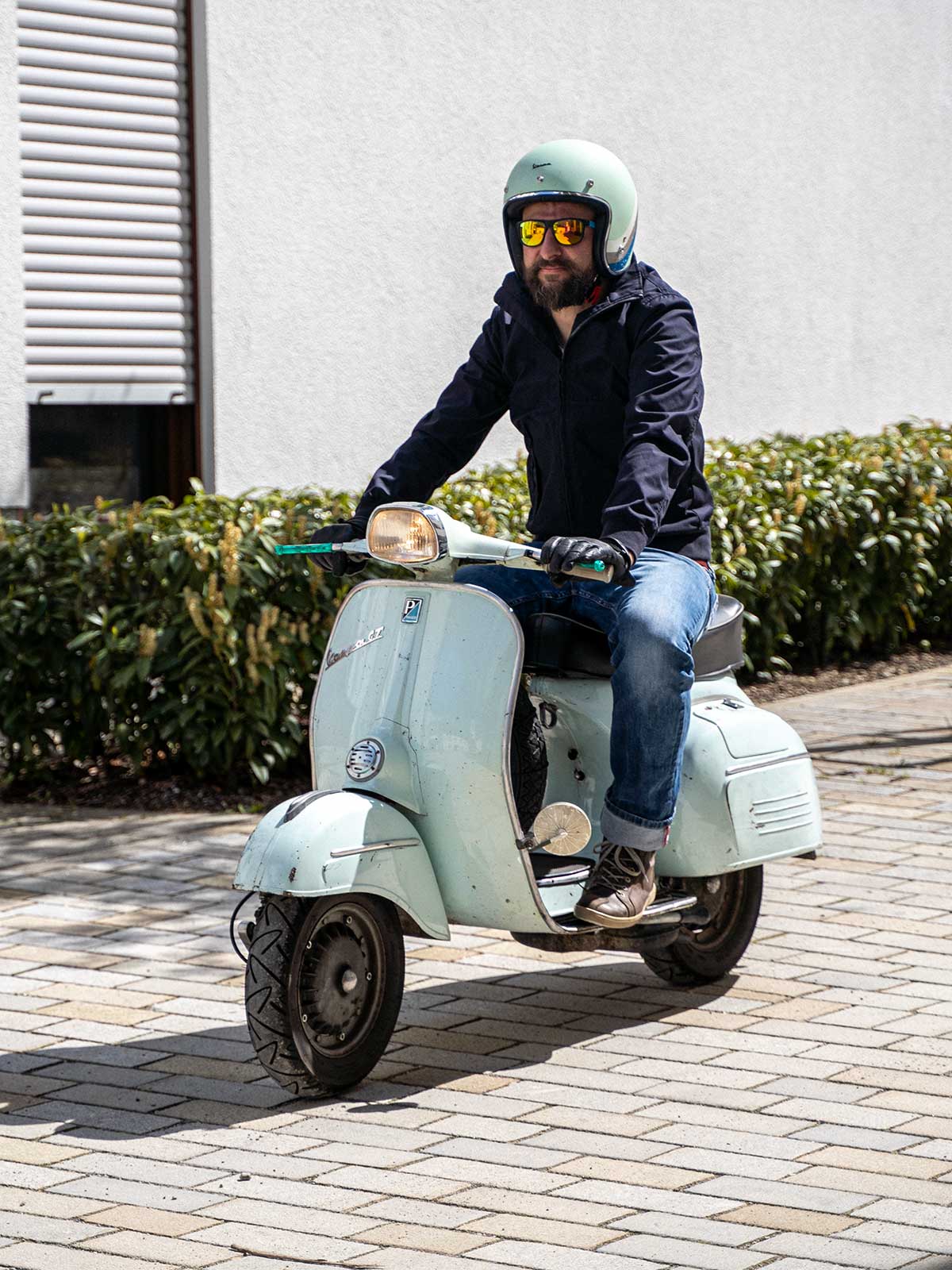 Ein Mann fährt auf einer Vespa und trägt einen abriebfesten Blouson der Marke For-Legends by Caduff, ideal für urban mobility - for-legends.com. A man rides a Vespa wearing an abrasion-resistant Blouson by For-Legends by Caduff, ideal for urban mobility - for-legends.com