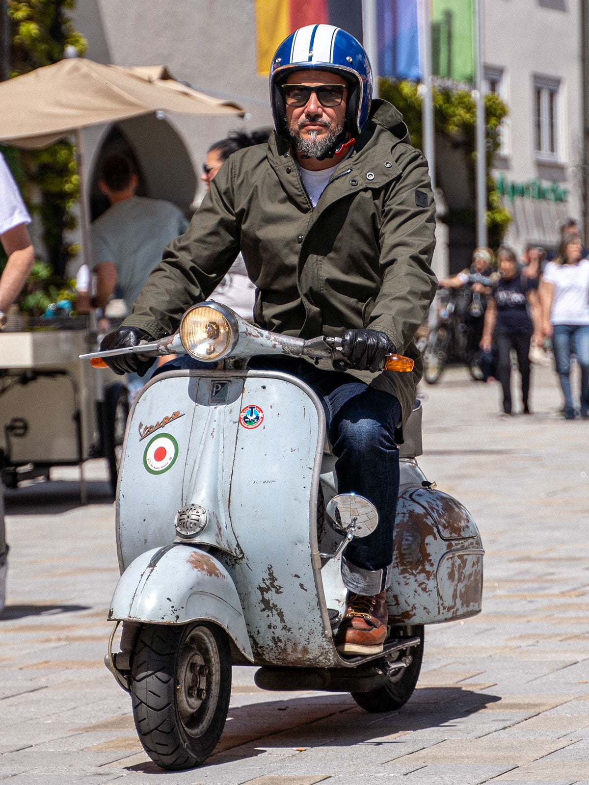 Ein Mann fährt auf einer Vespa | Scooter und trägt einen abriebfesten Parka der Marke For-Legends by Caduff, ideal für urban mobility - for-legends.com. A man rides on a Vespa / Scooter wearing an abrasion-resistant parka by For-Legends by Caduff, ideal for urban mobility - for-legends.com