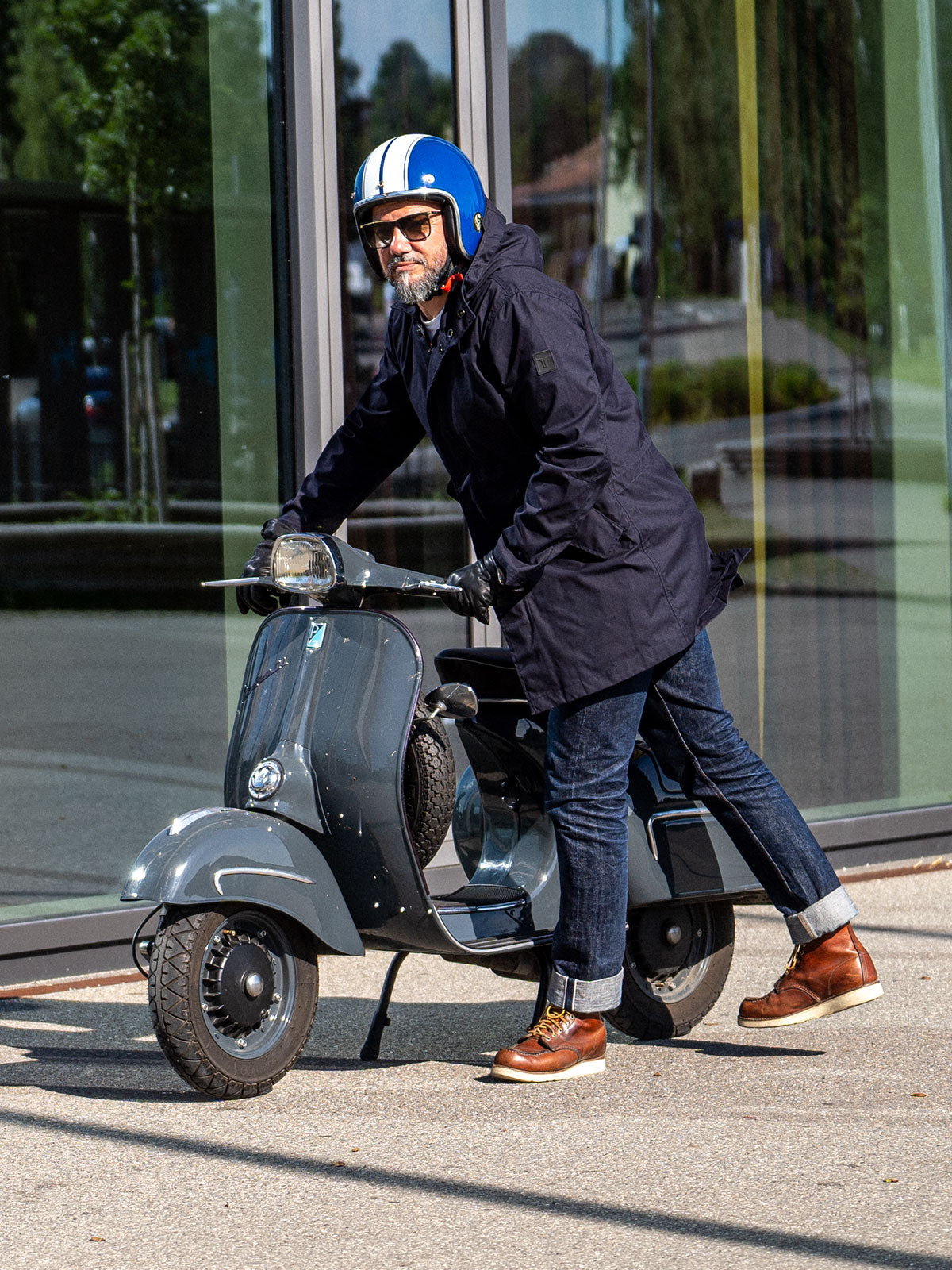Ein Mann fährt auf einer Vespa | Scooter und trägt einen abriebfesten Parka der Marke For-Legends by Caduff, ideal für urban mobility - for-legends.com. A man rides on a Vespa / Scooter wearing an abrasion-resistant parka by For-Legends by Caduff, ideal for urban mobility - for-legends.com