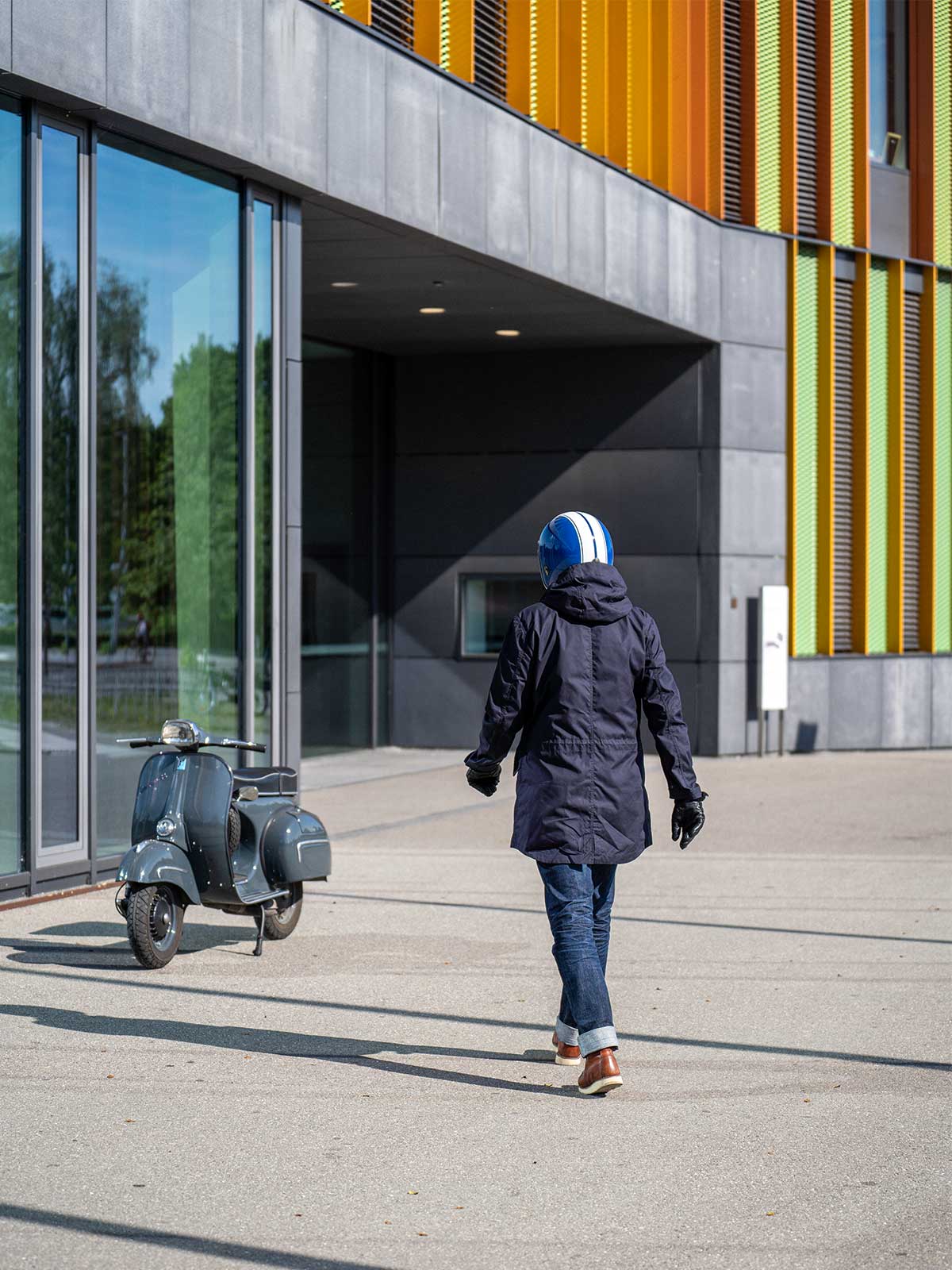 Ein Mann fährt auf einer Vespa | Scooter und trägt einen abriebfesten Parka der Marke For-Legends by Caduff, ideal für urban mobility - for-legends.com. A man rides on a Vespa / Scooter wearing an abrasion-resistant parka by For-Legends by Caduff, ideal for urban mobility - for-legends.com