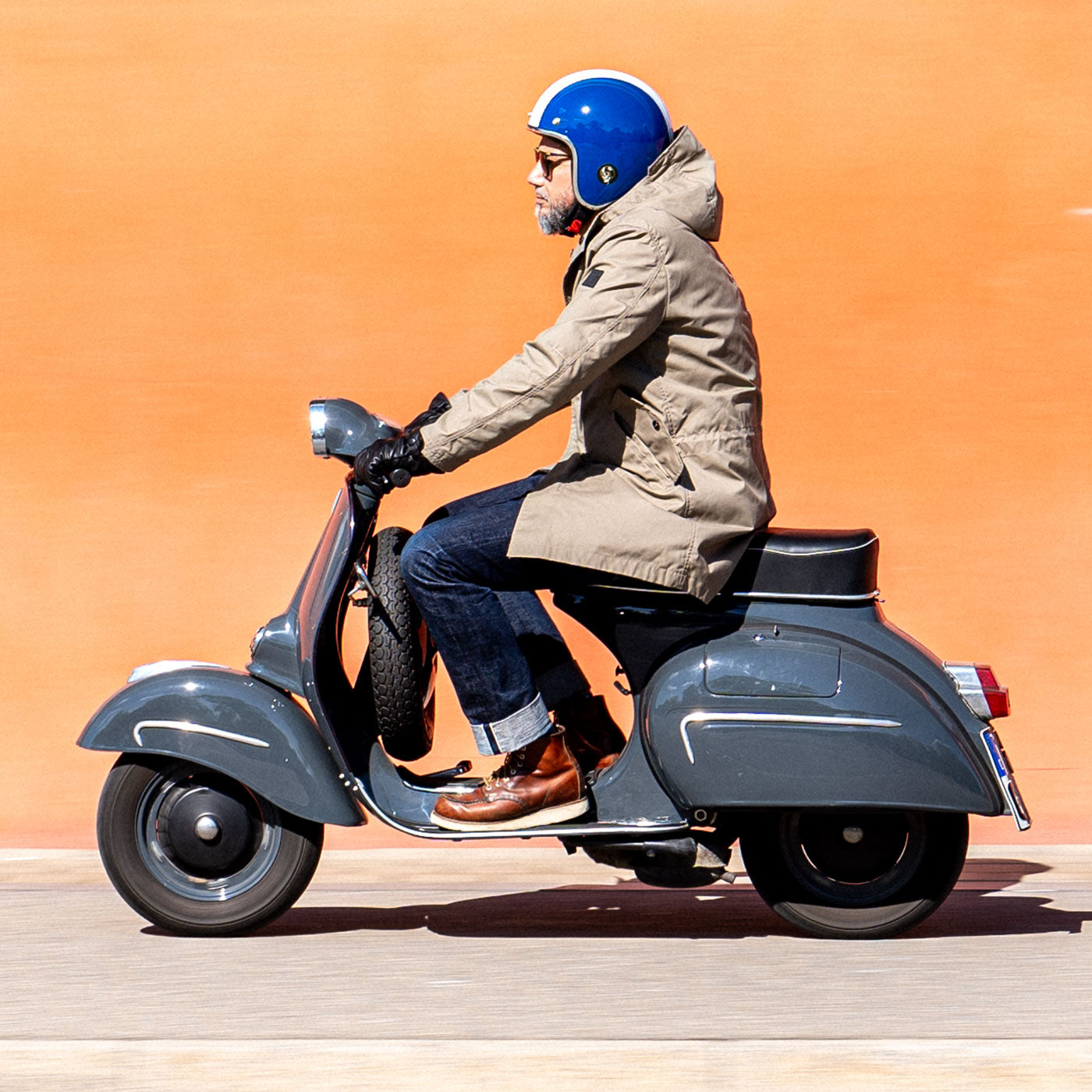 Ein Mann fährt auf einer Vespa und trägt einen abriebfesten Parka der Marke For-Legends by Caduff, ideal für urban mobility - for-legends.com. A man rides a Vespa wearing an abrasion-resistant parka by For-Legends by Caduff, ideal for urban mobility - for-legends.com.