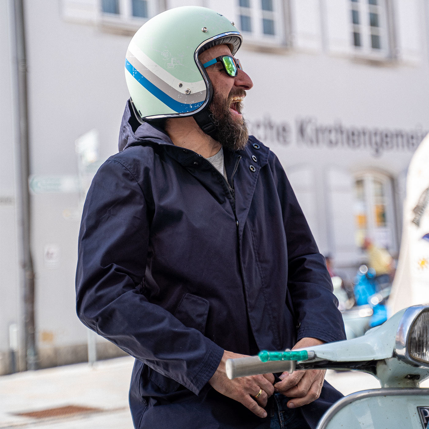 Ein Mann fährt auf einer Vespa | Scooter und trägt einen abriebfesten Parka der Marke For-Legends by Caduff sowie einen Back Protector von Orthema, ideal für urban mobility - for-legends.com. A man rides on a Vespa / Scooter wearing an abrasion-resistant parka by For-Legends by Caduff and a Back Protector from Orthema ideal for urban mobility - for-legends.com