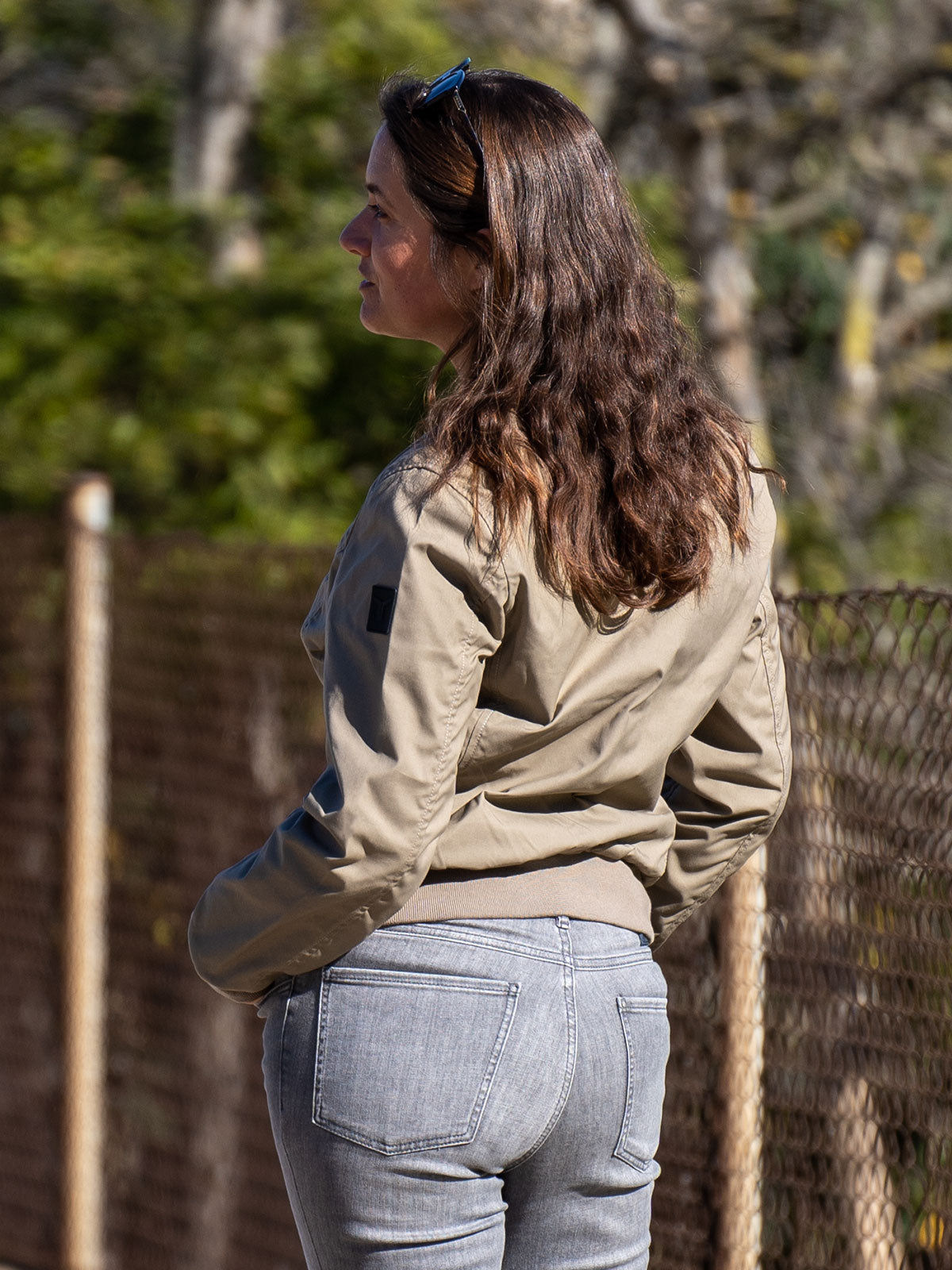 WOMAN MODEL WALKING WITH A SKATEBOARD IN THE CITY WEARING A MUD URBAN MOBILITY BOMBER JACKET FOR LEGENDS BY CADUFF