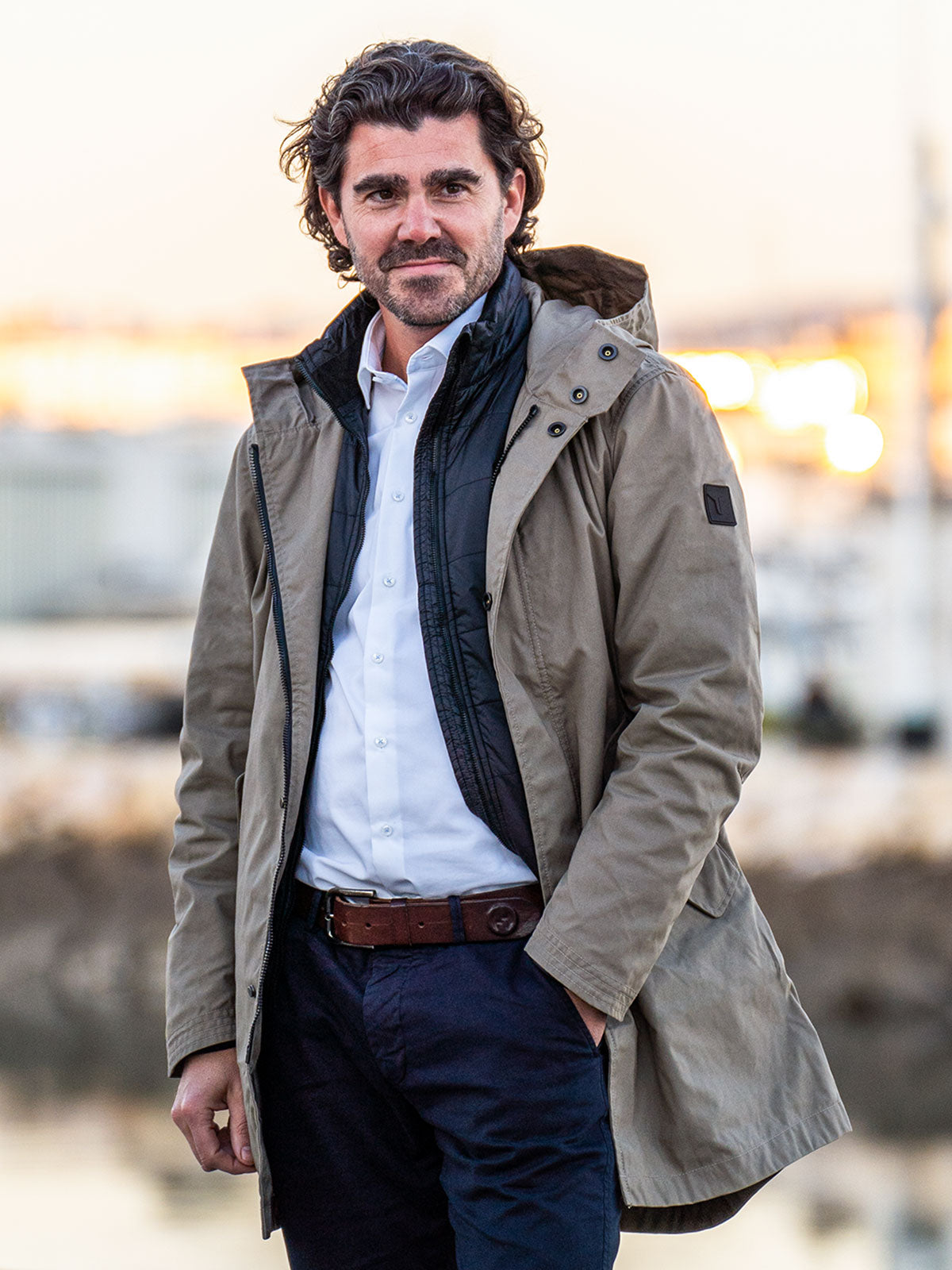 MODEL WALKING IN THE CITY WEARING AN URBAN MOBILITY PARKA WITH AN ABRASSION RESISTANCE UP TO A SPEED OF 45 KM/H