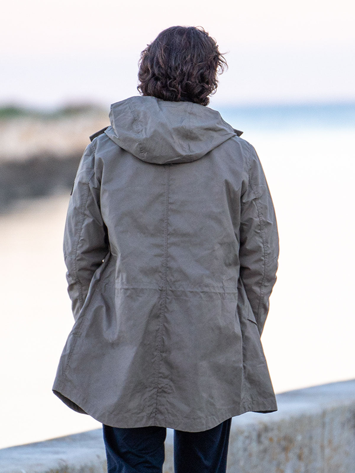 MODEL WALKING IN THE CITY WEARING AN URBAN MOBILITY PARKA WITH AN ABRASSION RESISTANCE UP TO A SPEED OF 45 KM/H