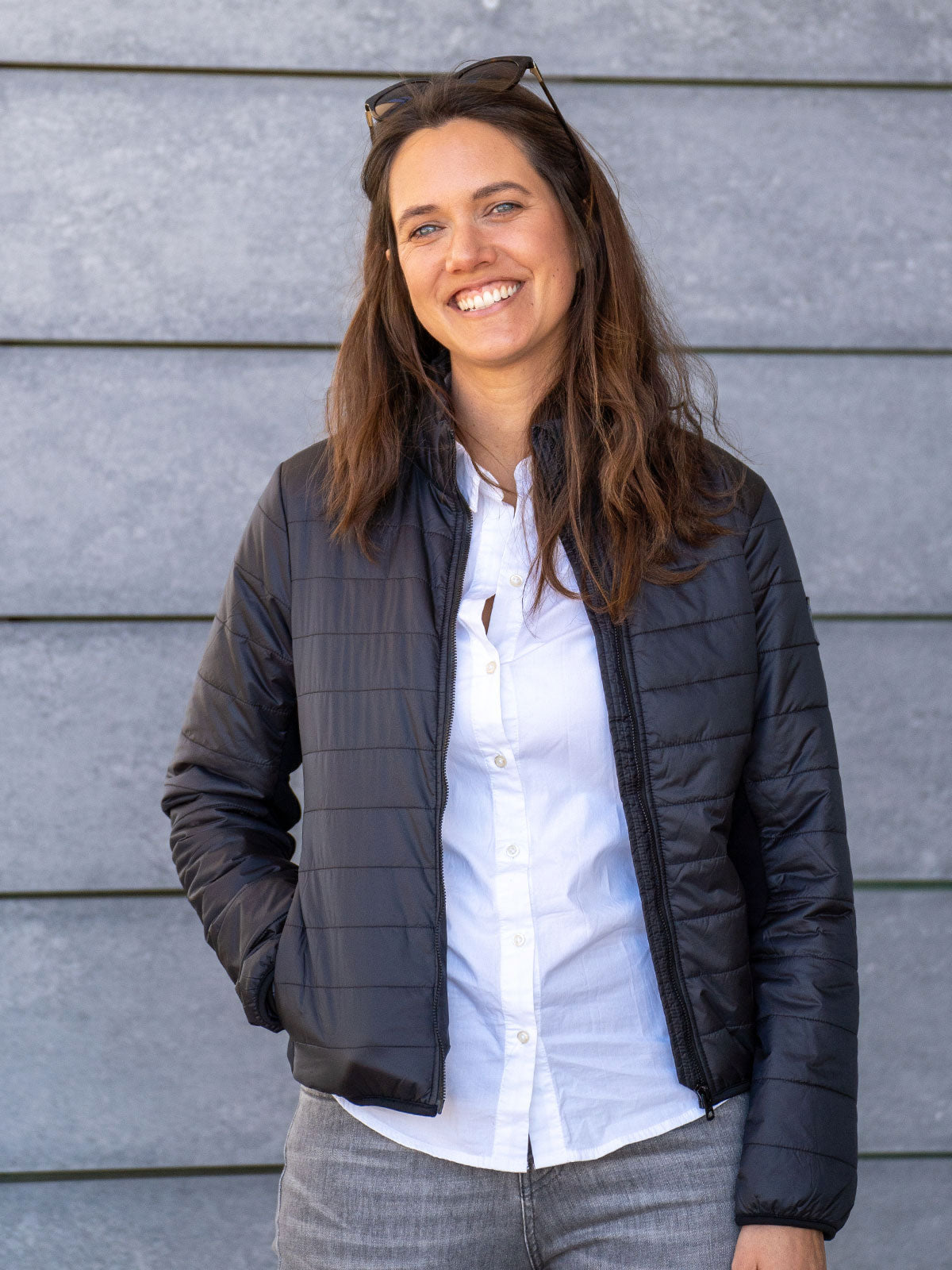 WOMAN MODEL STANDING IN THE CITY IN FRONT OF A HOUSE WEARING A ECO DOWN INSULATION JACKET WITH 100% RECYLED FIBRES FROM PET BOTTLES