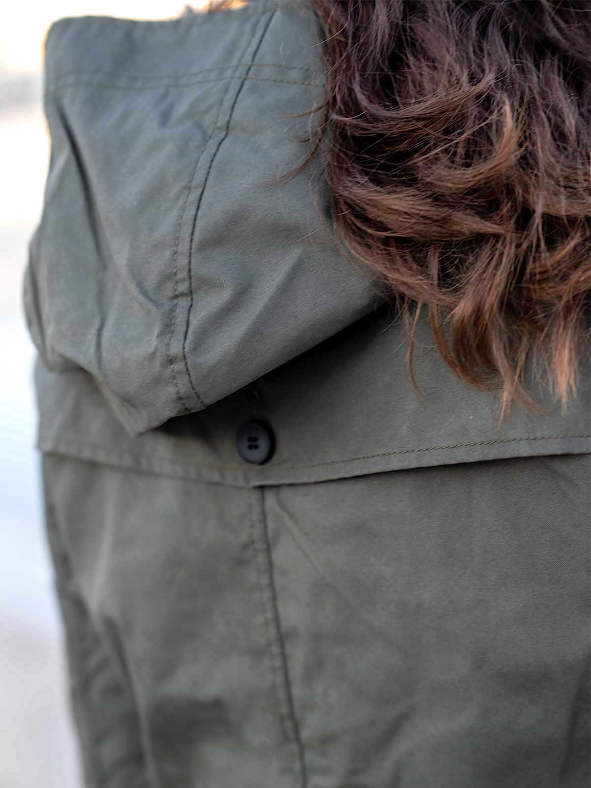 WOMAN WALKING AT THE HARBER WEARING AN URBAN MOBILITY PARKA WITH AN ABRASSION RESISTANCE UP TO A SPEED OF 45 KM/H