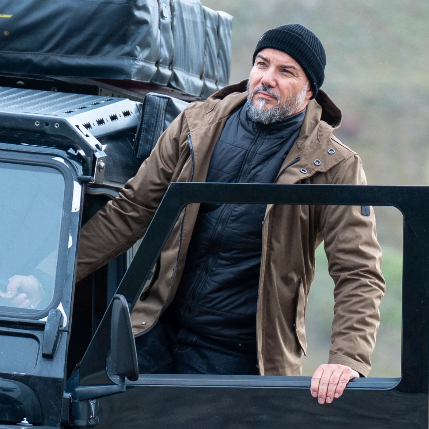 Model in the Beech CADUFF Japanese Double-Knit 2-in-1 Winter Parka getting into a black Land Rover Defender; the dense knit softens and patinas with wear.