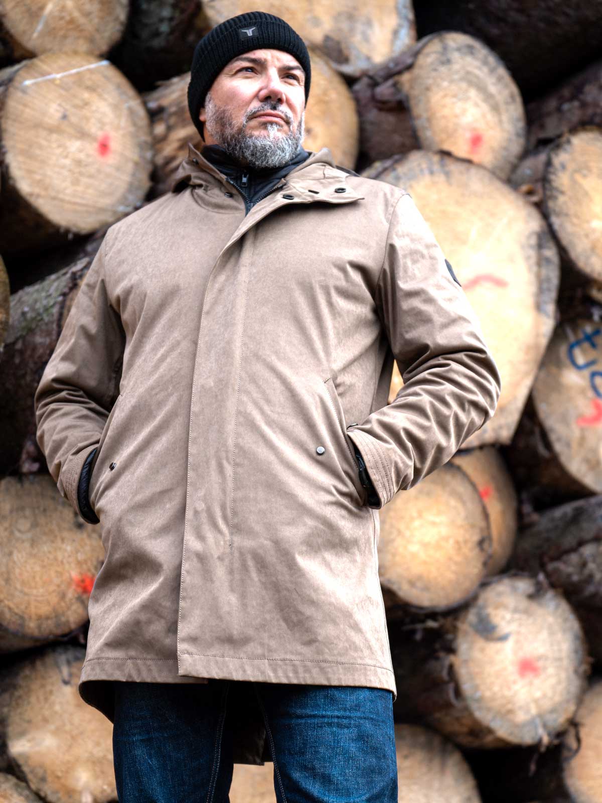 CADUFF Japanese Double-Knit 2-in-1 Winter Parka — Brown, front view against stacked timber; water-repellent and wind-resistant, removable ECO DOWN liner.