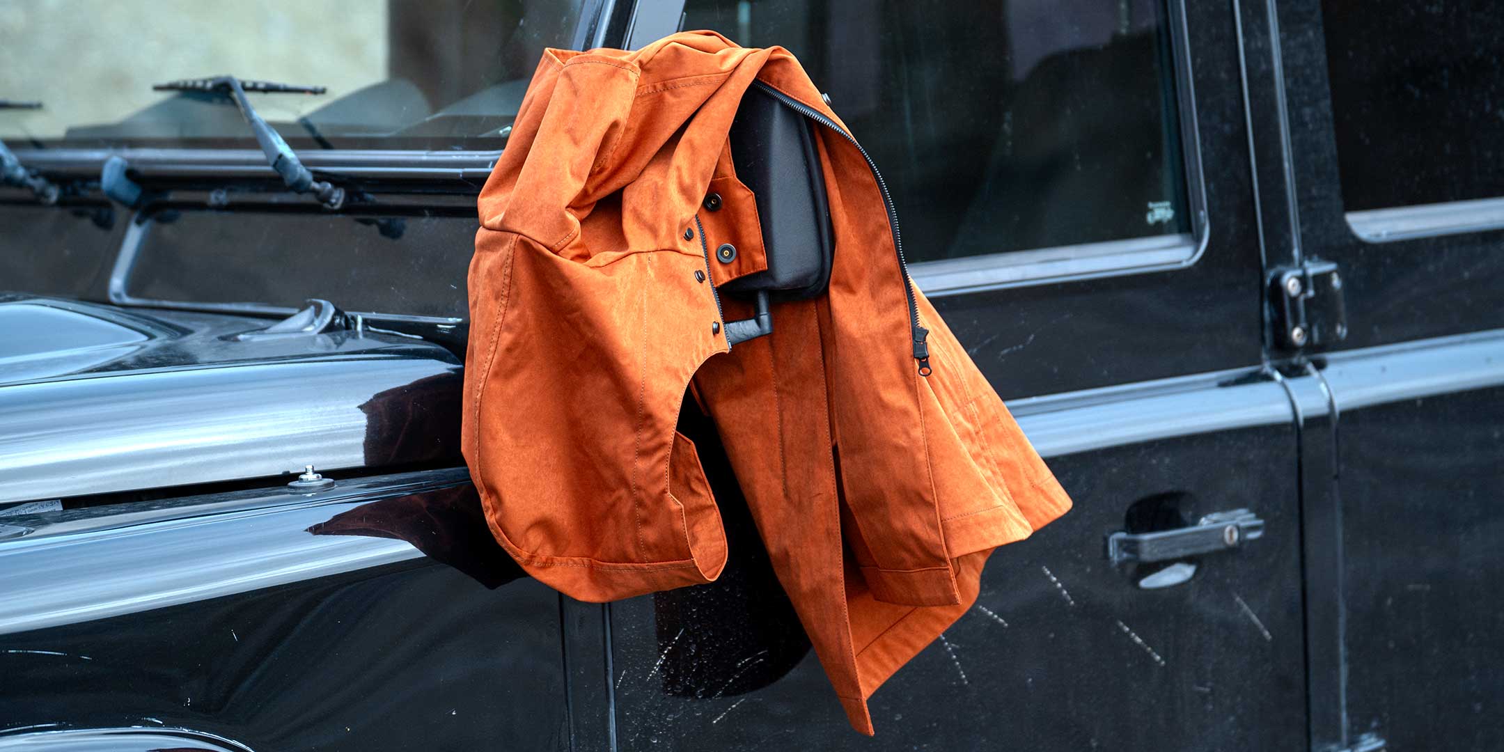 CADUFF Japanese Double-Knit 2-in-1 Winter Parka — Ginger; on-body shot beside a black Land Rover Defender; water-repellent, wind-resistant; removable ECO DOWN liner.