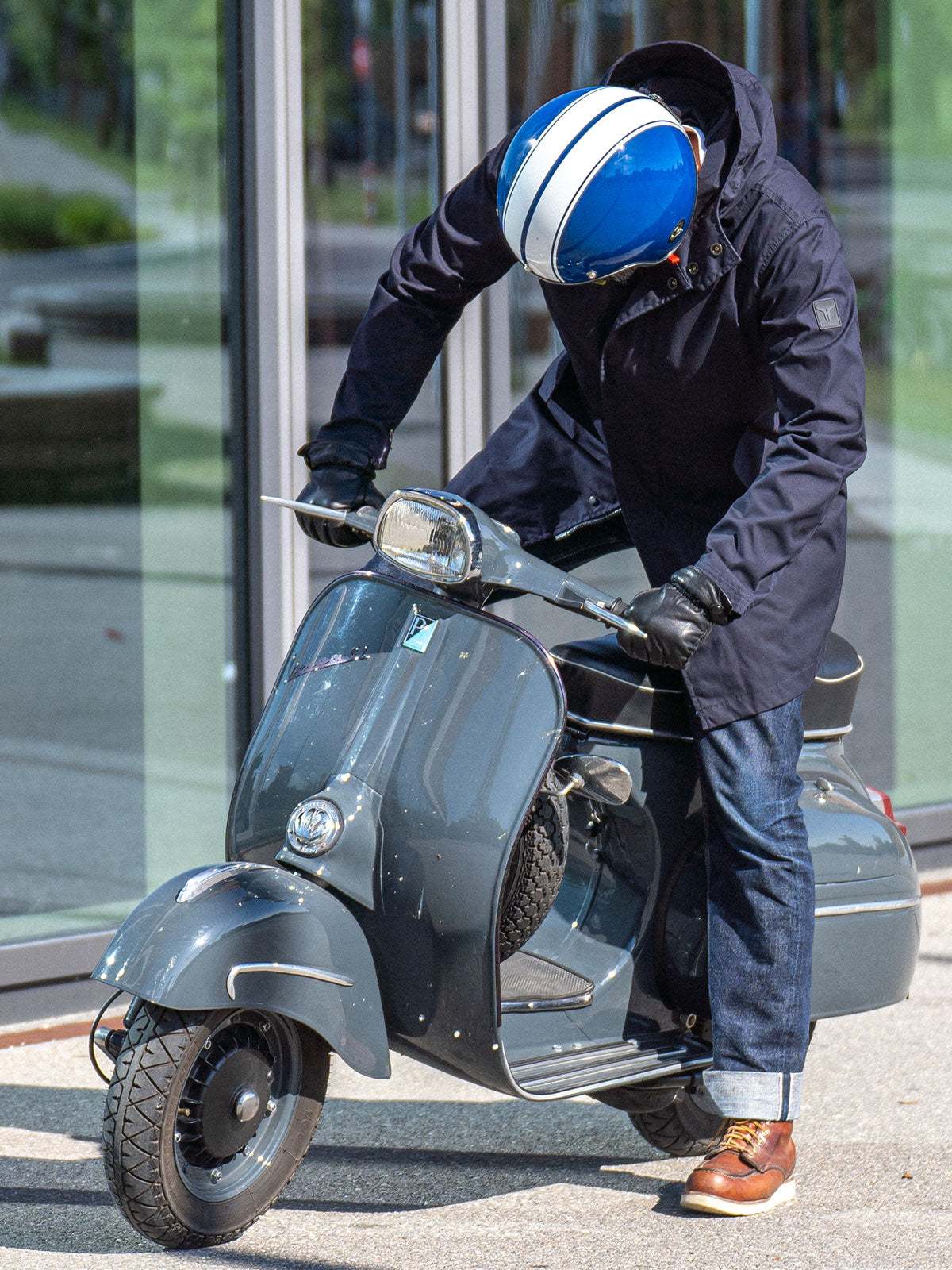 Ein Mann fährt auf einer Vespa | Scooter und trägt einen abriebfesten Parka der Marke For-Legends by Caduff, ideal für urban mobility - for-legends.com. A man rides on a Vespa / Scooter wearing an abrasion-resistant parka by For-Legends by Caduff, ideal for urban mobility - for-legends.com