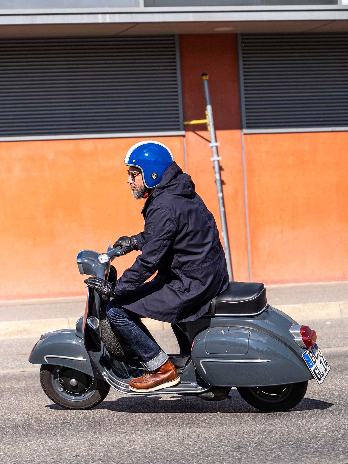 Ein Mann fährt auf einer Vespa | Scooter und trägt einen abriebfesten Parka der Marke For-Legends by Caduff, ideal für urban mobility - for-legends.com. A man rides on a Vespa / Scooter wearing an abrasion-resistant parka by For-Legends by Caduff, ideal for urban mobility - for-legends.com