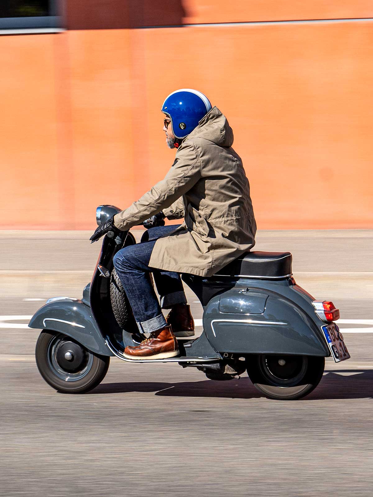 Ein Mann fährt auf einer Vespa | Scooter und trägt einen abriebfesten Parka der Marke For-Legends by Caduff, ideal für urban mobility - for-legends.com. A man rides on a Vespa / Scooter wearing an abrasion-resistant parka by For-Legends by Caduff, ideal for urban mobility - for-legends.com