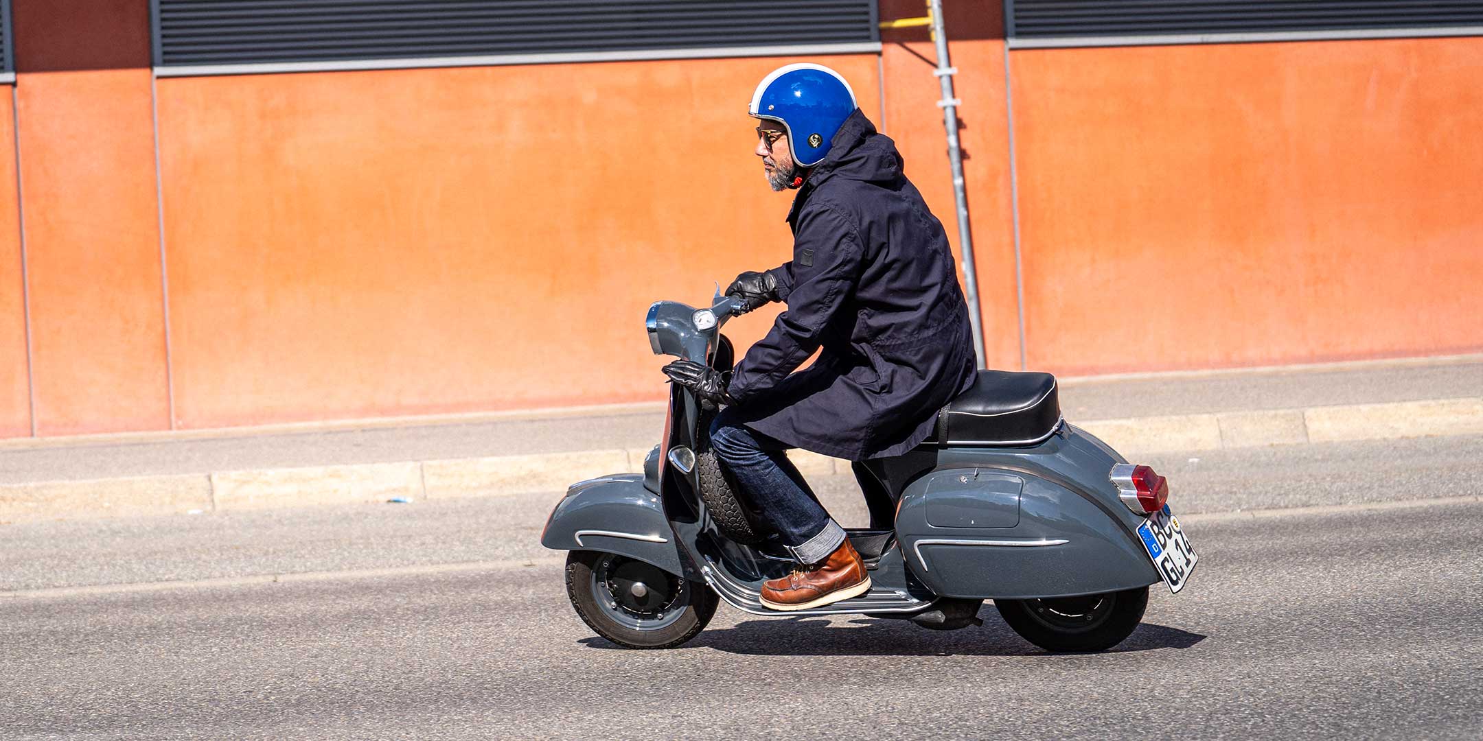 Ein Mann fährt auf einer Vespa | Scooter und trägt einen abriebfesten Parka der Marke For-Legends by Caduff, ideal für urban mobility - for-legends.com. A man rides on a Vespa / Scooter wearing an abrasion-resistant parka by For-Legends by Caduff, ideal for urban mobility - for-legends.com