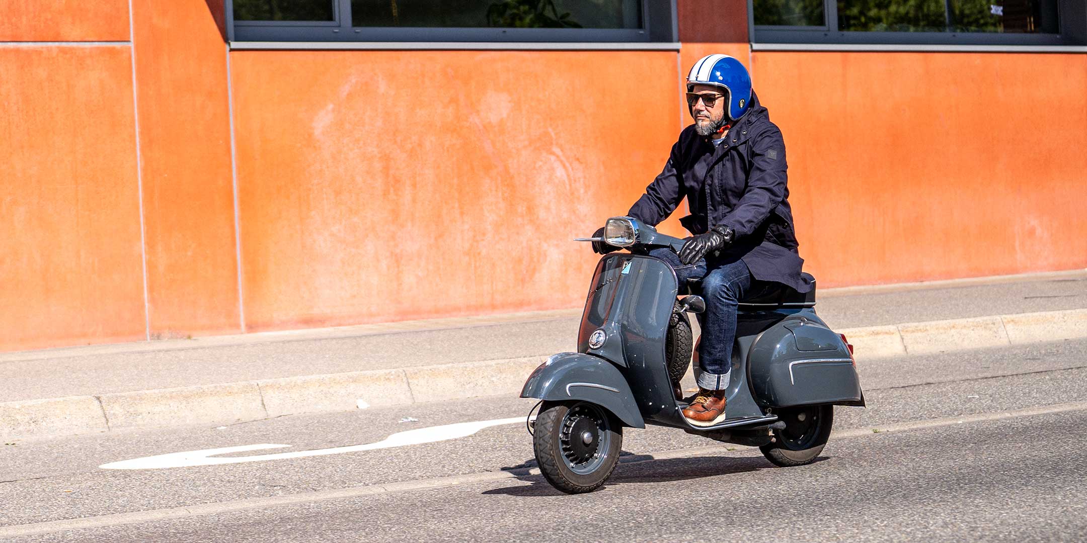 Ein Mann fährt auf einer Vespa | Scooter und trägt einen abriebfesten Parka der Marke For-Legends by Caduff, ideal für urban mobility - for-legends.com. A man rides on a Vespa / Scooter wearing an abrasion-resistant parka by For-Legends by Caduff, ideal for urban mobility - for-legends.com