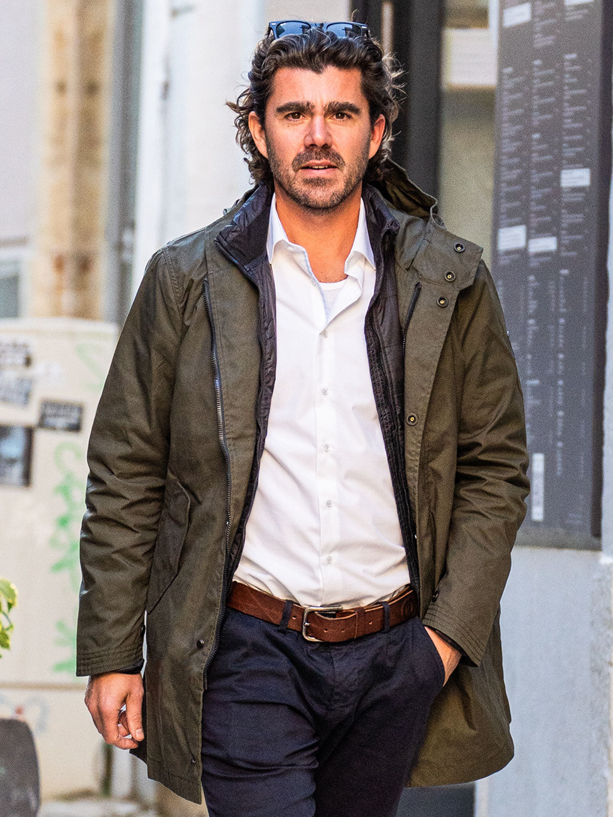 MODEL WALKING IN THE CITY WEARING AN URBAN MOBILITY PARKA WITH AN ABRASSION RESISTANCE UP TO A SPEED OF 45 KM/H