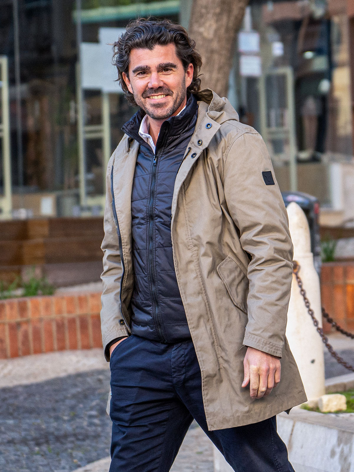 MODEL WALKING IN THE CITY WEARING AN URBAN MOBILITY PARKA WITH AN ABRASSION RESISTANCE UP TO A SPEED OF 45 KM/H
